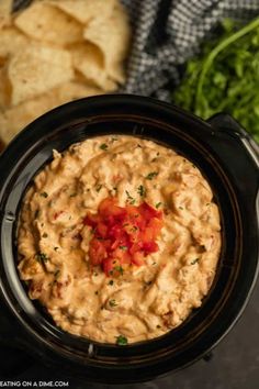 a black crock pot filled with guacamole dip and tortilla chips