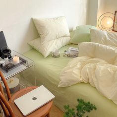 a laptop computer sitting on top of a bed covered in white sheets and pillow cases