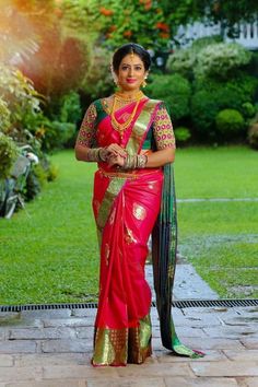 a woman in a red and green sari standing on a brick walkway with her arms crossed