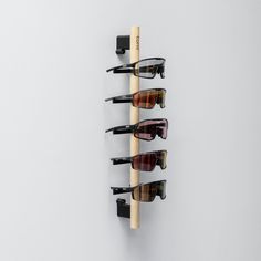 three pairs of sunglasses are hanging on a wall with wooden pegs and eyeglasses