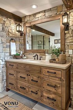 a rustic bathroom with stone walls and wood furniture, including a large mirror over the sink