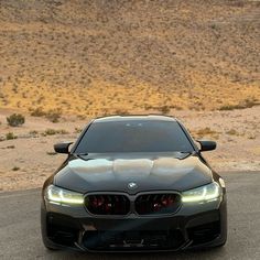 the front end of a black car on a desert road