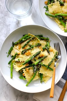 two plates of pasta with asparagus and parmesan cheese on the side