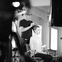 a woman getting her hair styled by a man in a black and white photo,