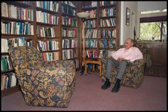 a man sitting in a chair next to a book shelf filled with books