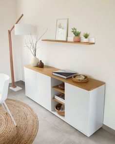 a living room with a white chair and wooden shelf on the wall next to a rug