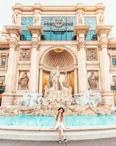 a woman sitting in front of a fountain