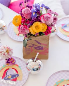 a table topped with plates and vases filled with flowers