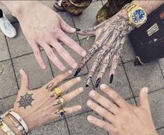 several hands with different designs on them and one has a clock tattooed on the palm