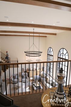 a living room filled with furniture and lots of windows next to a stair case in front of a chandelier