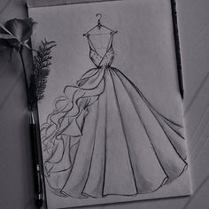 a drawing of a dress on a piece of paper next to a pen and flower