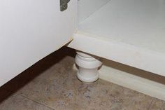 a white toilet sitting under a bathroom sink next to a cabinet with an open door