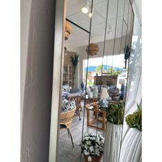 a large mirror reflecting the inside of a room with chairs and potted plants in it