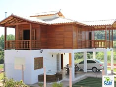 a white car is parked in front of a house with wooden balconies on the roof