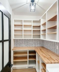 an empty walk in closet with wooden shelves