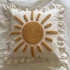 a white pillow with an embroidered sun on it