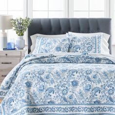 a bed with blue and white comforters in a bedroom next to a window,