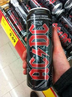 a person holding up a can of beer in front of a store shelf with other cans