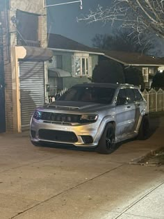 a silver jeep parked on the side of a road next to a house at night