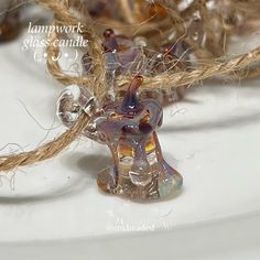 a glass figurine sitting on top of a white table next to some rope