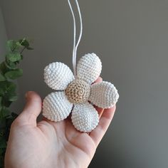 a hand holding a crocheted flower ornament