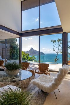 a living room filled with furniture next to a large glass window overlooking the ocean and mountains