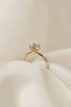 a gold ring with two diamonds on it sitting on top of a white cloth covered surface