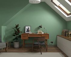 an attic office with green walls and wooden desk, chair, potted plant and window