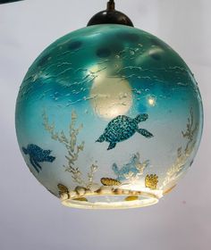 a glass ornament hanging from a ceiling with sea animals on it's side