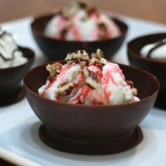 four desserts are arranged in small bowls on a plate