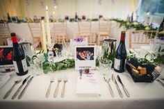 the table is set with silverware, wine bottles and photos on it for guests to take pictures