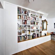 a white book shelf filled with lots of books on top of a hard wood floor