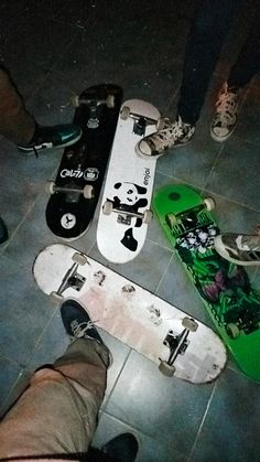 several skateboards laying on the ground with one person standing next to them and another sitting down