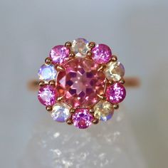 Pink Tourmaline Ring Pink spinel Rainbow Moonstone halo ring Edwardian style halo ring solid yellow gold pink engagement ring One-of-a-kind Pink Tourmaline Ring with Blue Moonstone and Pink Spinel Halo in 14K Rose Gold Add a touch of elegance to your jewelry collection with our custom designer cut natural pink tourmaline ring. The showstopper of this ring is a natural pink tourmaline, cut in a unique designer cut, measuring 6mm x 6mm. The tourmaline is surrounded by a double halo of blue moonsto Fine Jewelry Pink Halo Ring With Accent Stones, Pink Round Halo Ring With Accent Stones, Pink Halo Ring With Accent Stones, Fine Jewelry Pink Cluster Ring With Accent Stones, Pink Cluster Ring With Round Cut, Pink Sapphire Ring With Halo Setting And Round Cut, Pink Cluster Jewelry With Center Stone, Pink Sapphire Jewelry With Halo Design, Pink Round Cluster Ring With Halo Setting