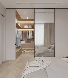 a bedroom with white walls and wooden flooring is shown in this image, there are clothes hanging on the closet doors