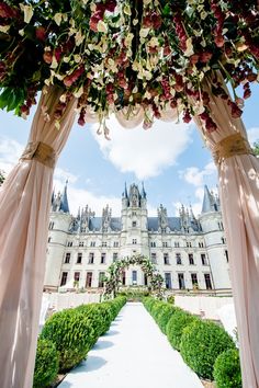 an outdoor wedding venue with pink drapes and flowers on the arch over the aisle