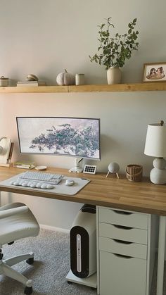 a desk with a computer on top of it next to a lamp and potted plant