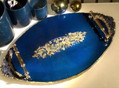 a blue tray sitting on top of a table next to cups and vases filled with gold flakes