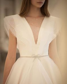 the back of a woman's wedding dress with sheer sleeves and beaded belt