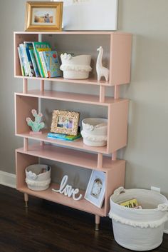 a pink shelf with books and pictures on it