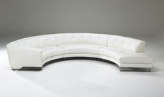 a curved white leather couch with chrome legs and foot rests on an empty floor in front of a gray background