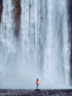 a person standing in front of a large waterfall