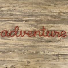 the word adventure written in red thread on wood