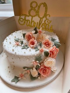 a white cake with pink flowers on top and the number thirty six spelled out in gold