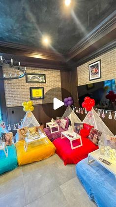 a room filled with lots of pillows and stuffed animals on top of each other in front of a flat screen tv