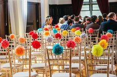 rows of chairs with pom - poms on them in front of a room full of people