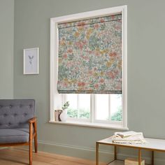 a living room with a chair, window and flowered blind in the window sill