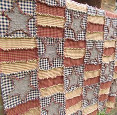 an old quilt is hanging on the side of a building with grass in front of it