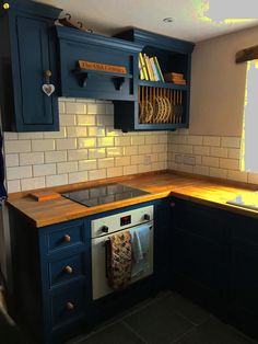 a kitchen with blue cabinets and wooden counter tops is pictured in this image, there are books on the shelves above the sink