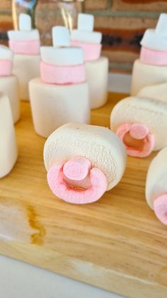 marshmallows with pink and white icing are arranged on a cutting board